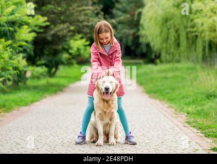 Kleines Mädchen, das mit Hund zwischen den Füßen steht Stockfoto