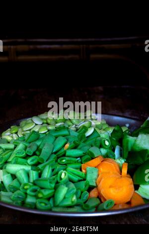 Frisches Gemüse schneiden die Stücke in den Teller auf hölzern Hintergrund Stockfoto