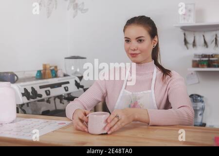 Eine fröhliche Barista, die Kaffee serviert und in einem lokalen Café arbeitet Stockfoto