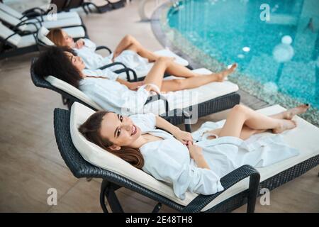 Schöne Dame Entspannung in der Nähe Pool mit ihren zwei Freundinnen Stockfoto