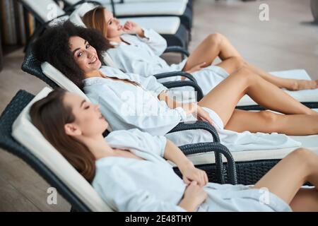 Attraktive lockige Frau am Pool mit Freunden entspannen Stockfoto