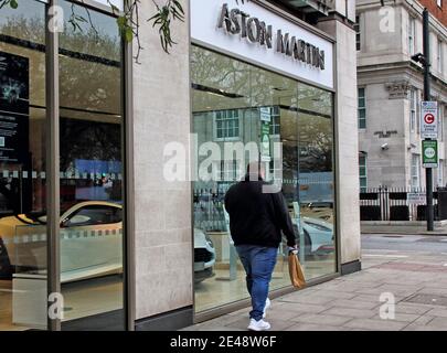 London, Großbritannien. Januar 2021. Ein Mann geht an einem Aston Martin Händler entlang Park Lane vorbei.England bleibt unter Lockdown als der Premierminister Boris Johnson weigert sich auszuschließen, dass es nach Ostern und in den Sommer fortsetzen kann, haben Covid-19 Fälle in der letzten Woche gefallen, Aber Großbritannien hatte gestern eine Rekordzahl von 1820 Toten. Kredit: SOPA Images Limited/Alamy Live Nachrichten Stockfoto