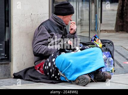 London, Großbritannien. Januar 2021. Ein Obdachloser sitzt auf dem Bürgersteig entlang Oxford Street.England bleibt unter Lockdown als der Premierminister Boris Johnson weigert sich auszuschließen, dass es nach Ostern und bis in den Sommer fortsetzen, Covid-19 Fälle sind in der letzten Woche gefallen, Aber Großbritannien hatte gestern eine Rekordzahl von 1820 Toten. Kredit: SOPA Images Limited/Alamy Live Nachrichten Stockfoto