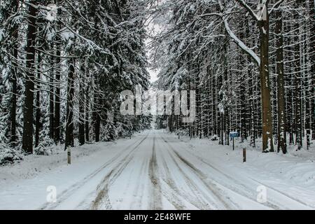 Gefährliche Strecke der Straße mit Schnee und Eis bedeckt.Snowy Straße durch Wald.Winterpanorama.Fahren in eisigen gefrorenen Landschaft.schlechte Wetterbedingungen. Stockfoto