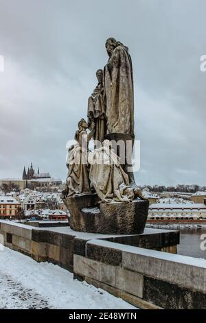 Prag, Tschechische Republik - 14. Januar 2021. Statuen auf der Karlsbrücke, Prager Burg im Hintergrund. Berühmte touristische Destination.Prag Winterpanorama. Stockfoto