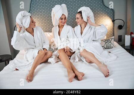 Drei beste Freunde, die sich nach einem heißen Bad auf dem Bett ausruhen Stockfoto