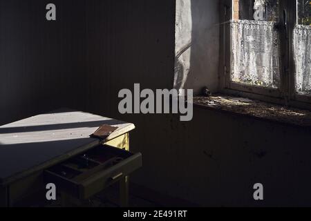 Aufnahme eines verlassenen Hauses mit einem alten Tisch und Holzfenster Stockfoto