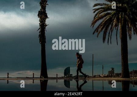 Barcelona, Spanien. Januar 2021. Ein Pendler spaziert nach einem regnerischen Sturm am fast menschenleeren Strand von Barcelona. Quelle: Matthias Oesterle/Alamy Live News Stockfoto