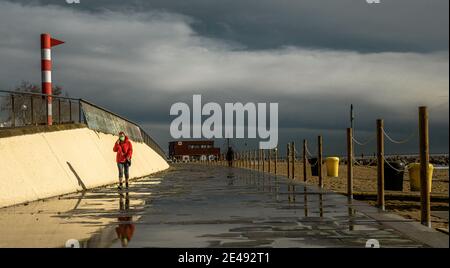 Barcelona, Spanien. Januar 2021. Ein Pendler spaziert nach einem regnerischen Sturm am fast menschenleeren Strand von Barcelona. Quelle: Matthias Oesterle/Alamy Live News Stockfoto