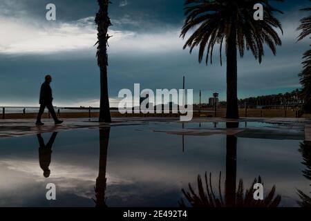 Barcelona, Spanien. Januar 2021. Ein Pendler spaziert nach einem regnerischen Sturm am fast menschenleeren Strand von Barcelona. Quelle: Matthias Oesterle/Alamy Live News Stockfoto