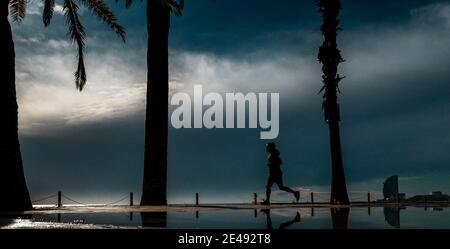 Barcelona, Spanien. Januar 2021. Ein Pendler joggt an Barcelonas fast menschenleeren Strand nach einem regnerischen Sturm. Quelle: Matthias Oesterle/Alamy Live News Stockfoto