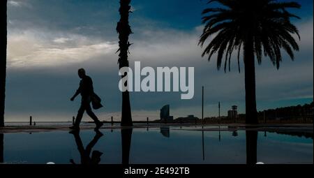 Barcelona, Spanien. Januar 2021. Ein Pendler spaziert nach einem regnerischen Sturm am fast menschenleeren Strand von Barcelona. Quelle: Matthias Oesterle/Alamy Live News Stockfoto