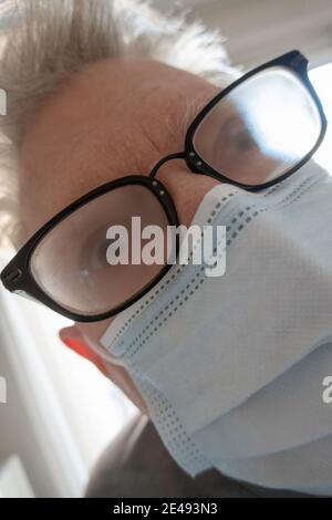 Älterer Mann mit Gesundheits- und Sicherheitsbedenken trägt eine schützende Gesichtsmaske mit beschlagener Brille New York City, USA Stockfoto