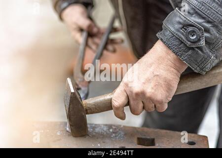 Ein Schmied schmiedet ein Hufeisen auf einem Amboss. Stockfoto