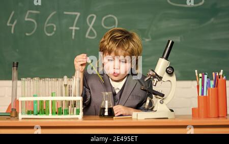 Technologie und Wissenschaft Konzept. Junge in der Nähe von Mikroskop und Reagenzgläser in der Schule Klassenzimmer. Kind studiert Biologie und Chemie in der Schule. Schulbildung. Erforschen Sie biologische Moleküle. Kleinkind Genie Baby. Stockfoto