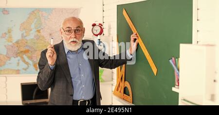 Gute Idee. High School moderne Bildung. Senior Mann Lehrer verwenden Lineal beim Zeichnen. Tutor Mann in Brille zeichnen mit Lineal auf Tafel. Zurück zur Schule. Welchen Winkel Sie sehen. Geometrische Formen. Stockfoto