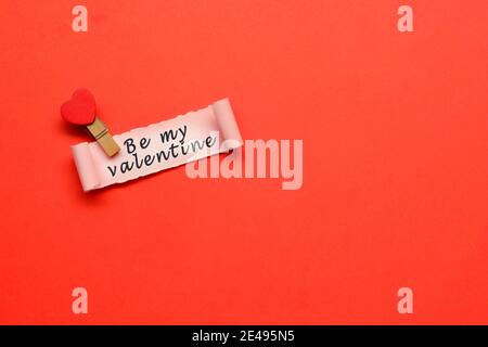 Be my Valentine Label auf zerrissenem Papier mit rotem Papierhintergrund Stockfoto