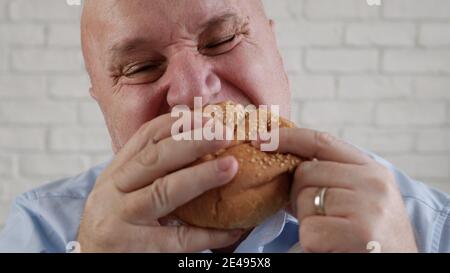 Hungrig Mann Essen einen leckeren Hamburger, genießen Sie einen köstlichen Snack in einem Fast Food Restaurant Stockfoto