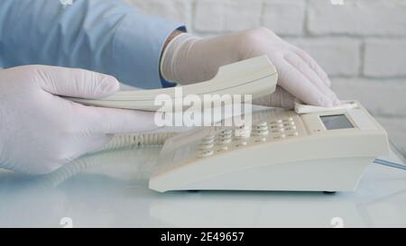Mann trägt Schutzhandschuhe in den Händen Reinigung und Desinfektion eines Telefons mit einem Spray und feuchten Wischtüchern Stockfoto