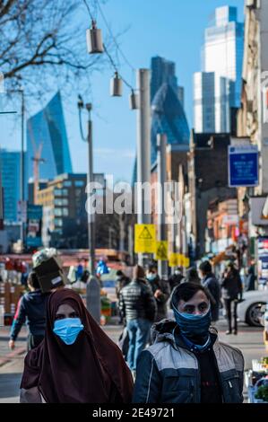 London, Großbritannien. Januar 2021. Die Leute sind unterwegs auf Whitechapel Road, einige einkaufen, einige plaudern, während der nationalen Lockdown 3. Über ihnen sind gelbe Warnschilder, die darauf hinweisen, dass Sie Abstand halten. Kredit: Guy Bell/Alamy Live Nachrichten Stockfoto