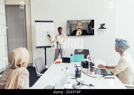 Geschäftsfrau, die Kollegen im Büro und über Video vorführt Anrufen Stockfoto