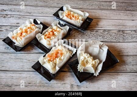 Vorspeise mit Lachs und Garnelen in rechteckigen schwarzen Kunststoffschalen, Tageslicht Stockfoto