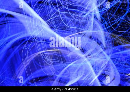 Mehrschichtige Linien, Wirbel und Streifen von blauen und weißen Farben, die von LED-Leuchten erzeugt wurden, die nachts im Freien fotografiert wurden. Stockfoto