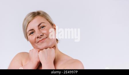 Banner. Eine nette ältere Frau mit gesunder und feuchtigkeitsspendender Haut schaut auf die Kamera und lächelt. Weißer Hintergrund und leerer Seitenraum. Stockfoto