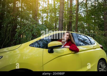 Glücklich lächelnde Frau Fahrer trägt roten Mantel sitzt in der Auto Stockfoto