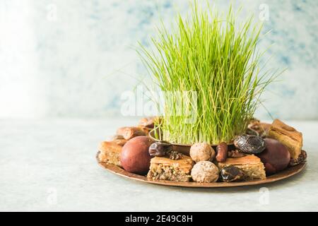 Novruz traditionelle Tablett mit grünem Weizengras semeni oder sabzi, Süßigkeiten und trockenen Früchten pakhlava auf weißem Hintergrund. Frühlings-Tagundnachtgleiche, Aserbaidschan copy sp Stockfoto