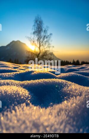 Landschaft bei Sonnenuntergang mit verschneiten Bergen und schneebedeckten Wiesen, Bäumen und Wald. Sonnenuntergang im Winter in den schneebedeckten Bergen mit Bäume Stockfoto