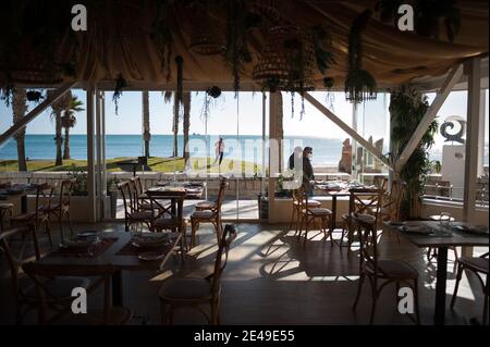 Malaga, Spanien. Januar 2021. Menschen, die an einem leeren Restaurant am Strand von La Malagueta vorbeigehen, inmitten einer Coronavirus-Pandemie.die Region Andausia erleidet einen unkontrollierten täglichen Anstieg von Coronavirus-Fällen, trotz harter Einschränkungen im täglichen Leben. In den letzten Wochen hat Andalusien täglich Tausende von Infektionen in der Region gemeldet, während der Krankenhausdruck weiter steigt. Kredit: SOPA Images Limited/Alamy Live Nachrichten Stockfoto