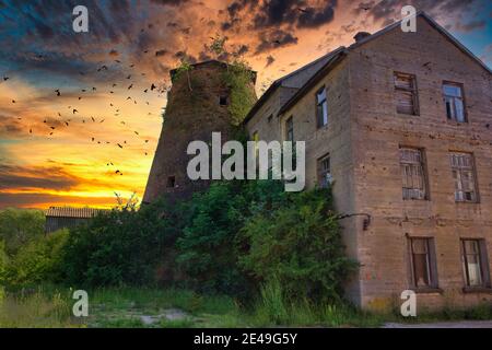 Alte kaputte Windmühle in dramatischem Sonnenuntergang Stockfoto