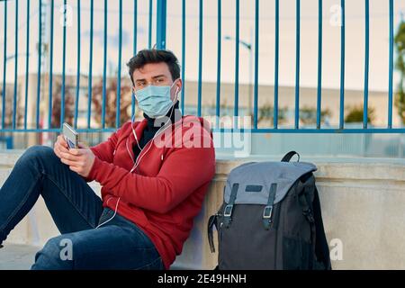 Ein Schüler mit einer Maske hört Musik auf einem Basketballfeld Stockfoto