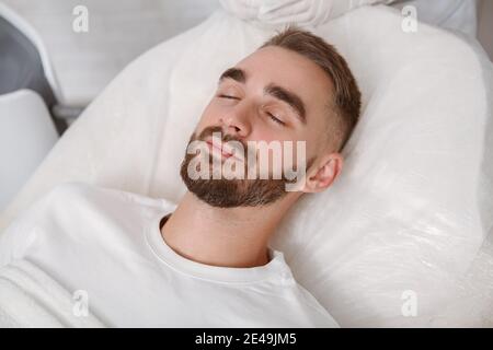 Schöner junger Mann, der nach der Operation in seinem Krankenhausbett schläft Stockfoto
