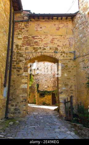 Ein steinerner Torbogen über eine ruhige Wohnstraße im historischen mittelalterlichen Dorf Montefioralle in der Nähe von Greve in Chianti in der Provinz Florenz, Toskana Stockfoto