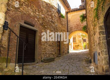 Ein steinerner Torbogen über eine ruhige Wohnstraße im historischen mittelalterlichen Dorf Montefioralle in der Nähe von Greve in Chianti in der Provinz Florenz, Toskana Stockfoto