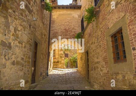 Ein steinerner Torbogen über eine ruhige Wohnstraße im historischen mittelalterlichen Dorf Montefioralle in der Nähe von Greve in Chianti in der Provinz Florenz, Toskana Stockfoto