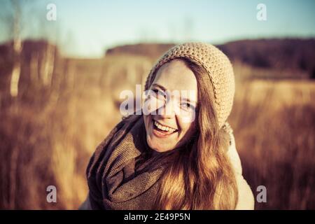 Lächelndes und glückliches Gesicht des jungen Mädchens draußen im Herbst Mit blauem Himmel im Hintergrund Stockfoto