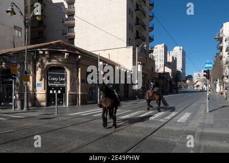 Israelische Polizisten der Kavallerieeinheit, die auf Pferden patrouillieren Entlang der leeren Jaffa Straße die längste Straße in der Innenstadt West Jerusalem inmitten von Covid-19 in Israel Stockfoto