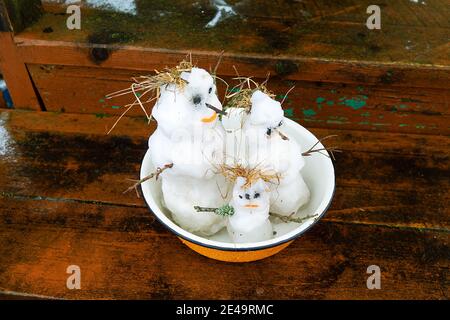 Winter-Frühling Geschichte der Schneemann-Familie: Schneemann-Vater, Schneemann-Mutter, Schneemann-Kind in der Küchenschüssel. Konzept des häuslichen Lebens Stockfoto