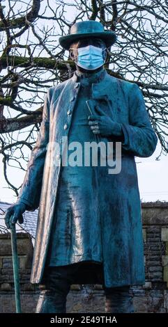 Coronavirus-Maske auf einer Statue von James Rice Buckley. Llandaff, Cardiff, Großbritannien Stockfoto