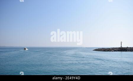 Leuchtturm am Eingang des Yachthafens von Antalya. Touristische Yacht im Meer in der Nähe des Leuchtturms im Hafen. Stockfoto