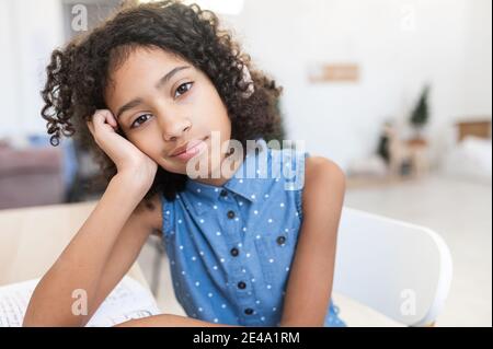 Ein Porträt gelangweilter afrikanischer weiblicher Kinder in Innenräumen. Ein Schulmädchen fühlt sich von monotonen Lektionen und vielen Hausaufgaben müde Stockfoto