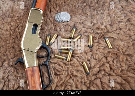 Altes Westhebel-Action Gewehr und Munition mit Silber-Dollar-Münzen Auf Skins-Hintergrund Stockfoto