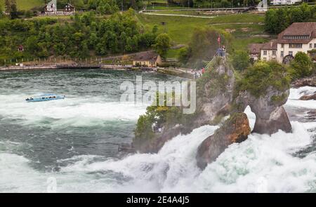 Rheinfall, Schweiz - 6. Mai 2017: Landschaftsfoto der Rheinfälle am bewölkten Frühlingstag, Touristen sind auf kleinen Felsen Stockfoto