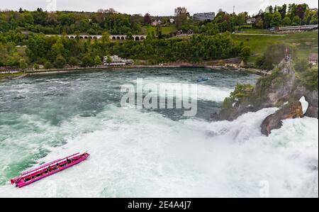 Rheinfall, Schweiz - 6. Mai 2017: Rheinfall bei bewölktem Tag macht ein Touristenboot mit Passagieren eine Rundreise Stockfoto