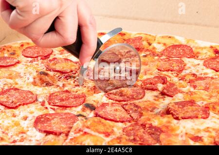 Weibliche Hand schneidet frische aromatische heiße italienische Mozzarella Pizza. Nahaufnahme Stockfoto