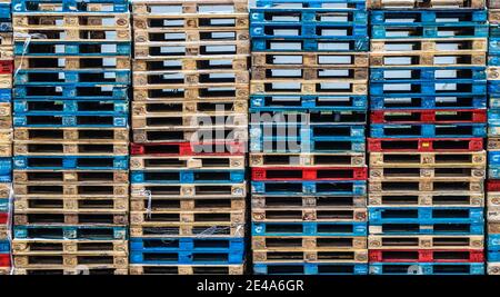 Euro-Holzpaletten in verschiedenen Farben in einer Reihe gestapelt, abstrakter Hintergrund Stockfoto