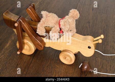 Handgefertigtes Holzkricket mit Teddybär, der oben auf reitet holzfußboden Stockfoto